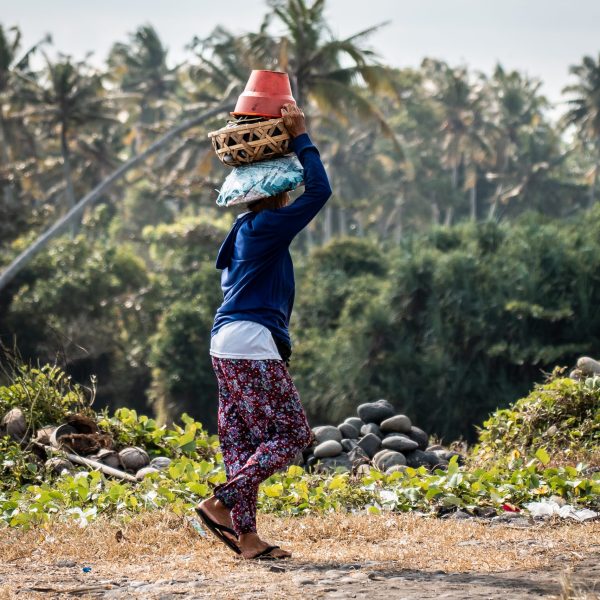 A local woman balancing a basket on her head near Abian Kapas Beach, Bali, Indonesia